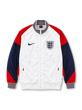 Front view of the England 2024/25 Nike Strike Anthem Jacket featuring a white body, red shoulders, navy sleeves, striped stand collar and cuffs, dark Nike Swoosh, Three Lions crest, full zipper, and zippered pockets.