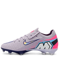 Nike Mercurial FG soccer cleats in lilac with a pink heel panel, pink paint-splatter accents, a navy-outlined holographic Swoosh, and Air Zoom heel lettering, plus a navy soleplate with a blue Air Zoom window, shown from the lateral side and outsole.