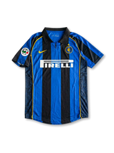 Front view of Inter home shirt in black and blue stripes with Pirelli sponsor, yellow swoosh, club crest, fold-over collar, and league sleeve patch.