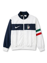 Italy national team Nike track jacket in white with wide navy horizontal chest band, navy stand collar, navy left sleeve, Italian tricolor flag stripe on right sleeve, white Swoosh at left chest, FIGC crest badge at right