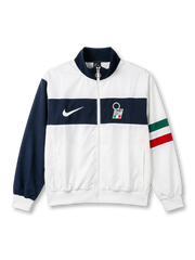Italy national team Nike track jacket in white with wide navy horizontal chest band, navy stand collar, navy left sleeve, Italian tricolor flag stripe on right sleeve, white Swoosh at left chest, FIGC crest badge at right