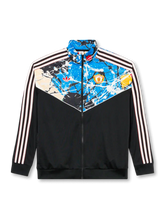 Manchester United × adidas Originals × The Stone Roses black track jacket with paint-splatter chevron yoke panel, red devil crest and Trefoil within the artwork, off-white Three Stripes on sleeves