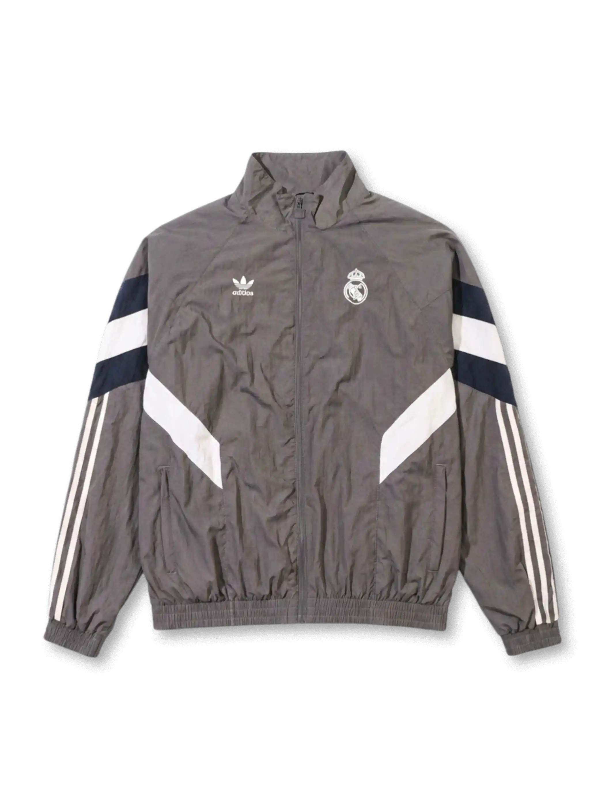 Real Madrid adidas Originals retro track jacket in charcoal grey with navy and white chevron panels, Trefoil logo and embroidered crest at chest, Three Stripes on sleeves