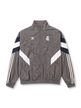 Real Madrid adidas Originals retro track jacket in charcoal grey with navy and white chevron panels, Trefoil logo and embroidered crest at chest, Three Stripes on sleeves