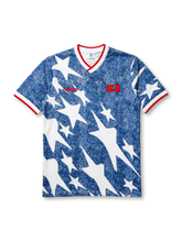 USA national team adidas Originals 1994 retro jersey with allover denim-blue star and lightning bolt print, red adidas wordmark at left chest, red USA script badge at right chest, red V-neck and sleeve cuff trim