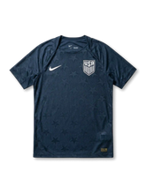 USA national team Nike 2026/27 Authentic (Player Issue) away jersey in navy with tonal allover star jacquard texture, white Swoosh at left chest, white USA shield crest at right chest, plain navy crew collar and cuffs, gold authentication label at lower right hem