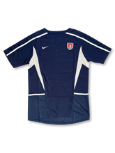 USA national team Nike training jersey in navy with white mesh side panels, white shoulder piping, Nike Swoosh at left chest, embroidered US Soccer shield crest at right chest