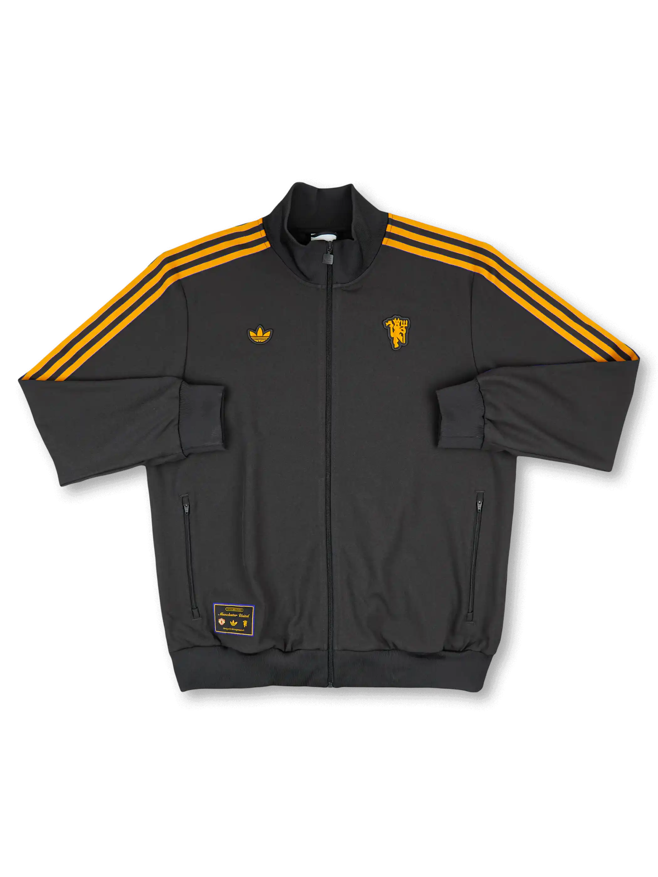 2025/26 Manchester United adidas Originals Icon short-sleeve track top in black with amber gold Three Stripes, gold standalone red devil crest at right chest, gold Trefoil at left chest, twin zip side pockets, and co-branded woven label at hem