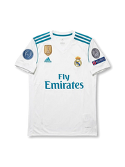 Front view of Real Madrid 2017-18 Champions League home shirt with white body, teal detailing, Fly Emirates sponsor, club crest, and European sleeve patches.