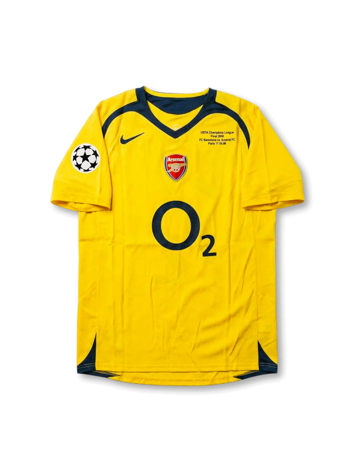 Front view of Arsenal 2006 Champions League Final away shirt with yellow body, O2 sponsor, Arsenal crest, Paris final match detail, and UEFA sleeve patch.