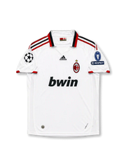 Front view of AC Milan 2009-10 away shirt with white body, red-and-black trim, bwin sponsor, club crest, and Champions League sleeve patches.
