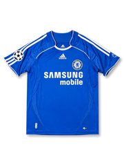 Front view of Chelsea 2006-07 home shirt with royal blue body, Samsung Mobile sponsor, Chelsea crest, white shoulder stripes, and UEFA Champions League sleeve patch.