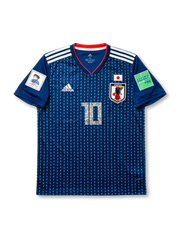 Front view of Japan 2018 Captain Tsubasa home shirt with blue pinstripe body, Japan crest, #10 illustrated number, white shoulder stripes, and FIFA sleeve patches.