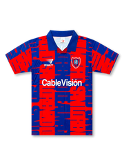 Front view of San Lorenzo 1990s graphic shirt with red and blue all-over pattern, club crest, Penalty logo, CableVisión sponsor, and blue fold collar.