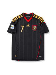 Front view of Germany 2010 World Cup away shirt with black base, gold shoulder stripes, red collar trim, Germany crest, front #7 print, and South Africa 2010 sleeve patch.