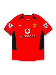 front view of Manchester United 2002-04 home shirt with red base, black side panels, Vodafone sponsor, club crest, and Premier League sleeve patches