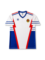 front view of Yugoslavia 1998 World Cup away shirt with white base, blue side panels, red geometric details, adidas trefoil logo, and national crest