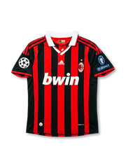 Front view of AC Milan home shirt in red and black stripes with white collar, bwin sponsor, adidas logo, club crest, and European competition sleeve patches.