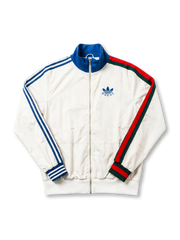 2022 adidas × Gucci collaboration off-white track jacket featuring blue Three Stripes on left sleeve, Gucci Web stripe in red-green-red on right sleeve, and co-branded Trefoil chest logo