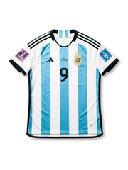 Front view of Argentina 2022 FIFA World Cup Final home shirt with sky blue and white stripes, black number 9, AFA crest, black shoulder stripes, final embroidery, and Qatar 2022 sleeve patches.