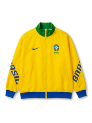 Brazil national team Nike track jacket in canary yellow with green stand collar, blue Nike Swoosh at left chest, CBF crest and BRASIL wordmark at right chest, bold BRASIL lettering running down both sleeves in royal blue, blue ribbed cuffs