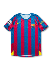 Front view of Barcelona 2005-06 Champions League Final home shirt with red and blue stripes, yellow swoosh, club crest, Champions League patch, and final sleeve embroidery.