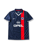 Paris Saint-Germain 2001-02 home jersey featuring Ronaldinho #21, Nike navy blue soccer shirt with an offset red vertical stripe, white V-neck detailing, OPEL sponsor logo, Nike Swoosh, PSG club crest, and RONALDINHO name and number 21 on the back of this retro soccer jersey.