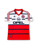 Bayern Munich 1998-00 away jersey featuring Lothar Matthaus #10, adidas soccer shirt with a white upper body, red lower section, navy horizontal stripes, red polo collar, red three-stripe shoulder detailing, black OPEL sponsor logo, Bayern Munich crest, and Bayern München lettering with Matthäus name and navy number 10 on the back.