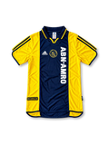 Front view of the 2000/01 Ajax centenary away soccer jersey in yellow and navy, featuring adidas three stripes, a navy polo collar, gold Ajax crest, and vertical white ABN AMRO sponsor.