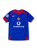 Front view of the 2005/06 Manchester United blue away soccer jersey by Nike, featuring red shoulder accents, a central club crest, white Vodafone sponsor, and UEFA Champions League sleeve patch.