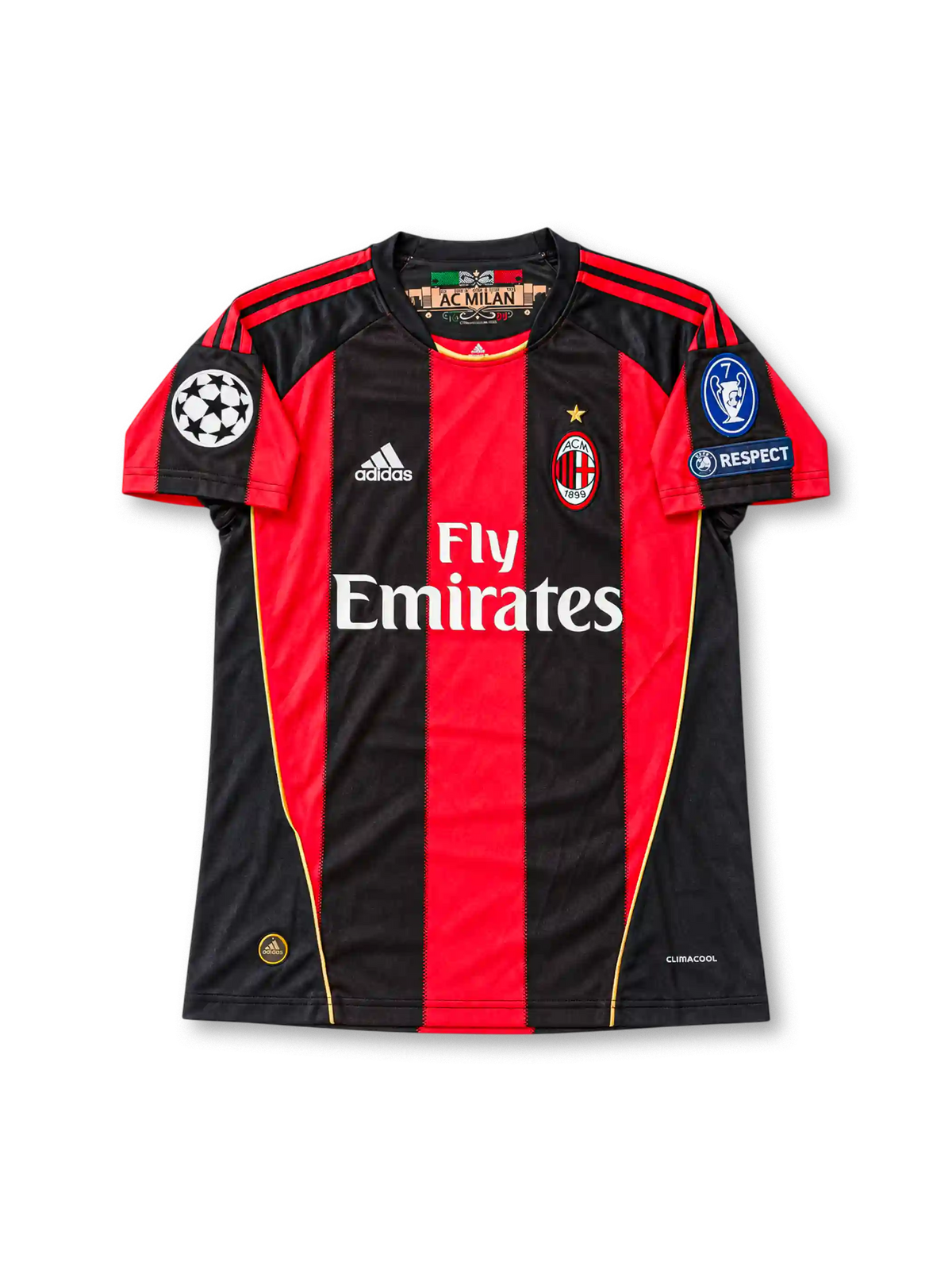 Front view of the 2010/11 AC Milan home soccer jersey featuring red and black vertical stripes, white adidas logo, Fly Emirates sponsor, club crest with gold star, UEFA Champions League starball patch, seven-time winners badge, and UEFA Respect patch.