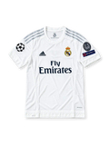 Front view of the Real Madrid 2015/16 white home soccer jersey featuring silver adidas shoulder stripes, dark navy Fly Emirates sponsor, crowned club crest, UEFA Champions League starball patch, 10-time European Cup winners badge, and UEFA Respect sleeve patch.
