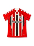 Front view of the River Plate 2003/04 away soccer jersey featuring red sleeves, red white and black vertical stripes, a black V-neck collar, white adidas shoulder stripes, River Plate crest, and Budweiser sponsor.