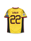 Front view of the AC Milan 2013-14 gold third football jersey featuring Kaká #22, black adidas shoulder stripes and side panels, red trim, Fly Emirates sponsor, Italian flag chest detail, and UEFA Champions League sleeve patches.