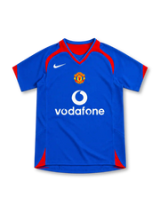 Manchester United 2005/06 royal-blue away jersey with red curved shoulder panels, red-trimmed V-neck collar, white Nike Swoosh, central club crest, white Vodafone sponsor and red side accents.