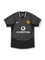 Manchester United 2003/05 Nike away jersey in black and charcoal grey with an all-over geometric pattern, white-trimmed collar and sleeve cuffs, white Nike Swoosh, Manchester United crest and Vodafone sponsor.