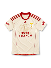 Galatasaray 2010/11 cream away jersey with tonal lion graphic, red adidas stripes and Türk Telekom sponsor