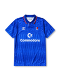 Chelsea 1989-91 home jersey, front view, royal blue body with diagonal jacquard texture, striped point collar, two-button placket, Umbro diamond logo, club lion crest, Commodore sponsor logo