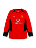 Manchester United 2002-04 home long sleeve jersey, front view, red body with black angular shoulder and side panels, black crew neck collar, black forearm panels, Nike swoosh logo, club crest, Vodafone sponsor logo