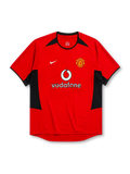 Manchester United 2002-04 home jersey, front view, red body with black angular shoulder and side panels, black crew neck collar, black sleeve trim, Nike swoosh logo, club crest, Vodafone sponsor logo