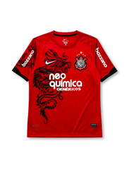 Corinthians 2011-12 third jersey, front view, red body with black São Jorge dragon graphic, black crew neck collar, Bozzano sleeve sponsor lettering, Nike swoosh, club crest with five stars, Neo Química Genéricos sponsor logo
