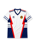 Yugoslavia 1990 World Cup away jersey, front view, white body with red and navy lightning bolt panels, navy V-neck collar, striped cuffs, adidas trefoil logo, national emblem