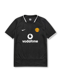 Manchester United 2003-04 away jersey, front view, black body with tonal geometric pattern, white ringer collar and cuffs, Nike swoosh logo, club crest, Vodafone sponsor logo