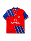 Bayern Munich 1993-95 home jersey, front view, red body with diagonal blue and white stripe panels, blue V-neck collar with white piping, white adidas Equipment logo, FC Bayern Munchen crest, white Opel sponsor logo, striped cuffs