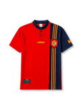 Spain 1996 home jersey, front view, red body with asymmetric navy side panel, navy button-placket collar, yellow adidas logo and stripes, Spanish royal crest, small Spain flag patch on sleeve, Federacion Espanola de Futbol tag near hem