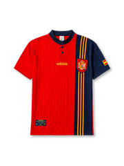 Spain 1996 home jersey, front view, red body with asymmetric navy side panel, navy button-placket collar, yellow adidas logo and stripes, Spanish royal crest, small Spain flag patch on sleeve, Federacion Espanola de Futbol tag near hem