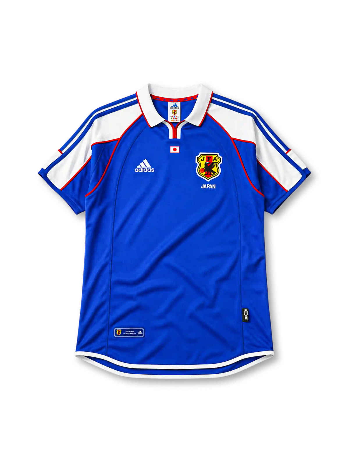 Japan 2000 home jersey, front view, blue body with white shoulder panels and red trim, white polo-style collar with red zip placket, small Japan flag emblem, JFA crest with three-legged crow, Japan text beneath crest