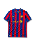 Barcelona 2009-10 home jersey, front view, blue and garnet vertical stripes, yellow-trimmed V-neck collar, white Nike swoosh, Barcelona crest, yellow unicef sponsor logo with globe emblem, yellow cuff trim