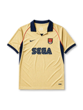 Arsenal 2001-02 away jersey, front view, gold body with navy side panels and red piping, navy V-neck collar, white Nike swoosh, Arsenal shield crest with cannon, navy Sega sponsor logo, navy cuffs