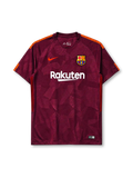 Barcelona 2017-18 third jersey, front view, deep maroon body with tonal geometric crackled pattern, orange shoulder accents, crew-neck collar, orange Nike swoosh, Barcelona crest, white Rakuten sponsor logo, black and red striped side panels